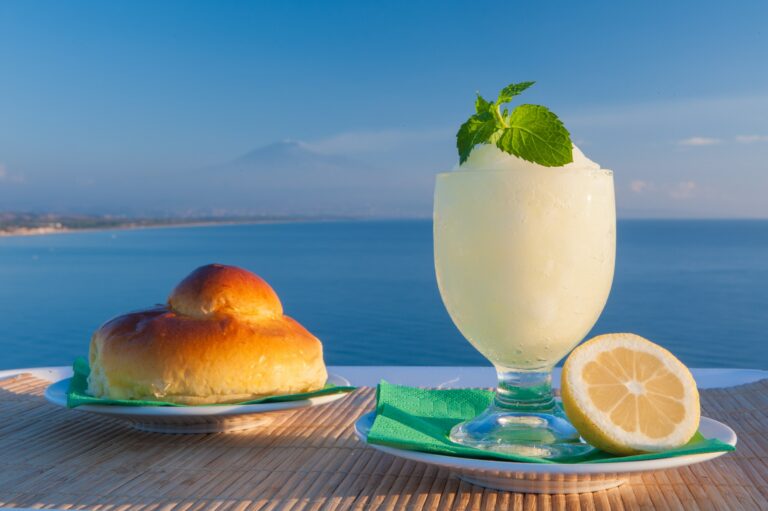 Sizilianische Granita al Limone mit Brioche und Zitrone vor dem Meer