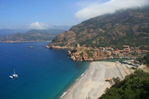 Der Strand von Porto unter den roten Bergen nahe Capo Rosso