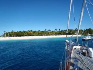 Grenadinen - Palmenstrand von Palm Island mit tuerkisem Wasser vom Segelschiff aus