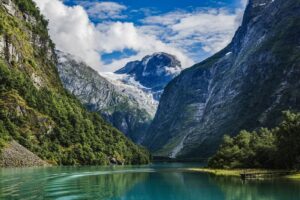 Olden, Norwegen - Gletscher und tuerkisfarbener Fjordsee im Oldedal umgeben von steilen Bergen