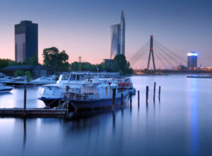 Riga - Skyline an der Düna mit Schrägseilbrücke und Bootsanleger in der Abenddämmerung