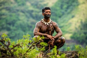 Tahuata - tätowierter Marquesaner in Tracht vor grüner Bergkulisse, Marquesas