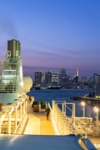 Tokio - Skyline mit beleuchtetem Tokyo Tower und Rainbow Bridge in der Abenddämmerung vom Schiffsdeck aus