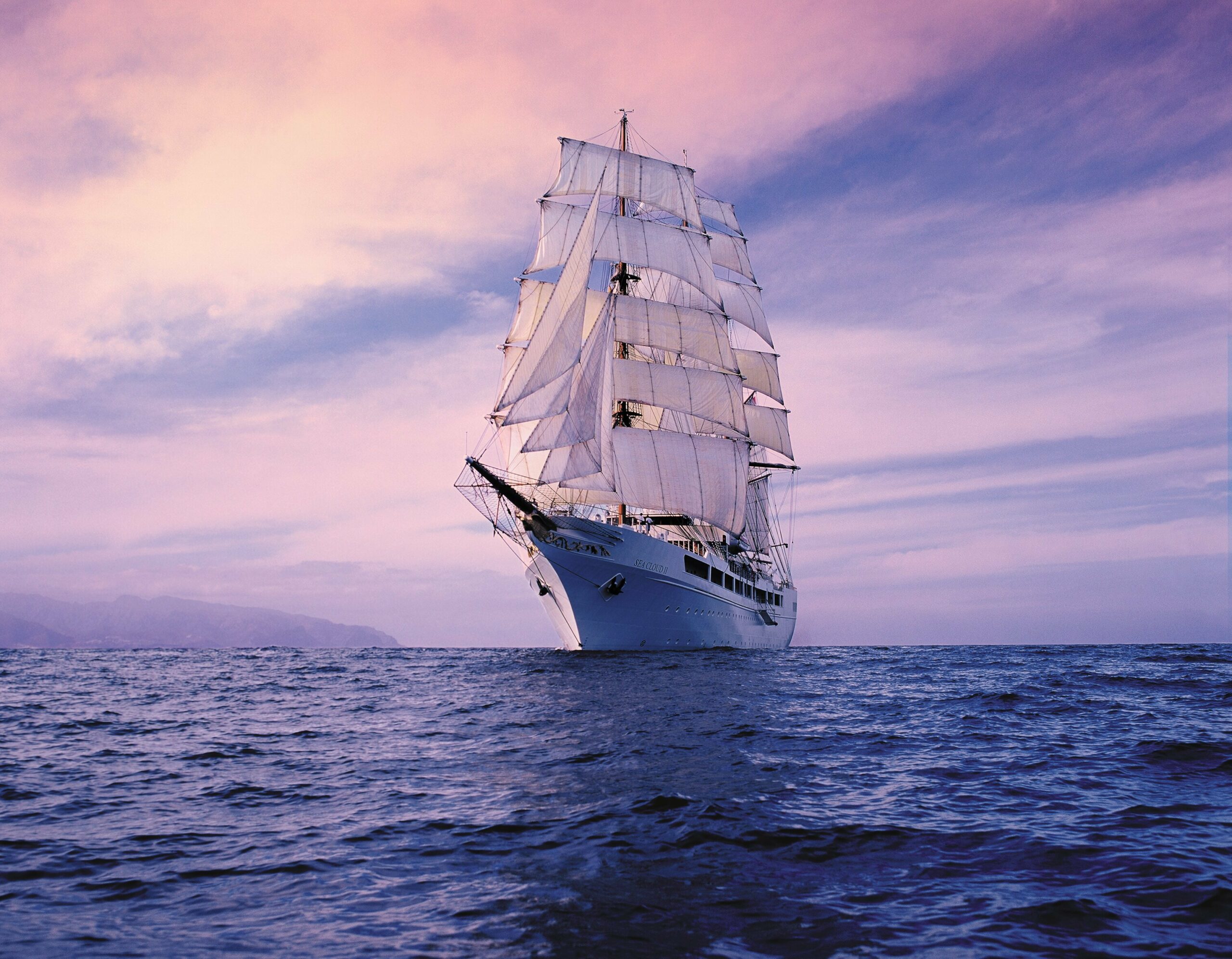 Die Sea Cloud II unter vollen Segeln in der Abenddämmerung