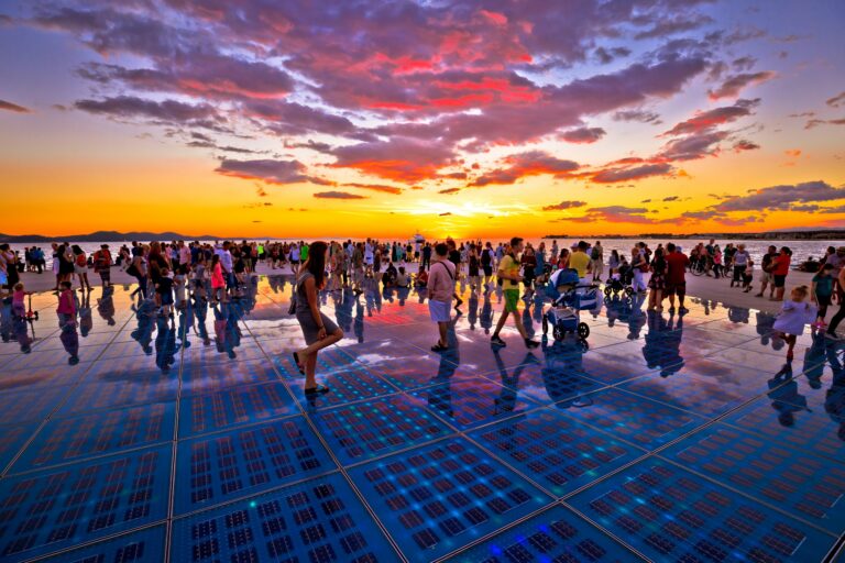 Sonnengruß und Meeresorgel an der Uferpromenade von Zadar bei Sonnenuntergang mit Spaziergängern